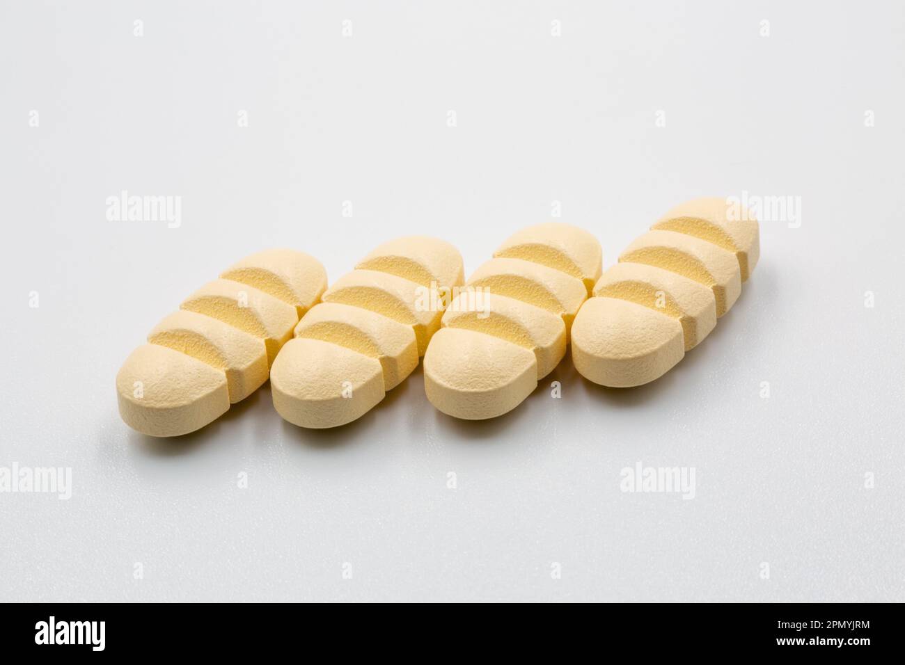 Yellow oblong tablets with dividing strips for dividing into four parts closeup on white. Stock Photo