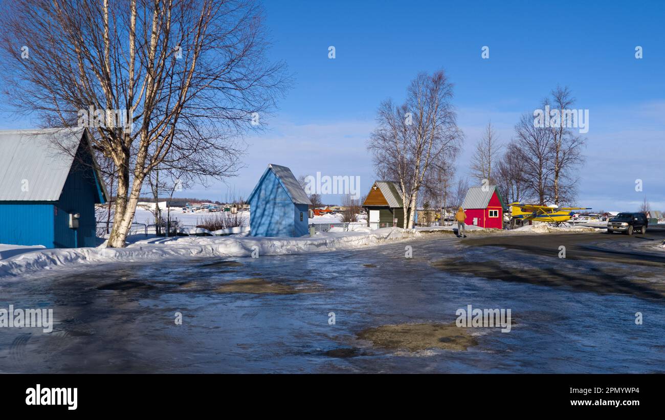 Blue and red wood cabins along the road covered with ice and snow. Stock Photo