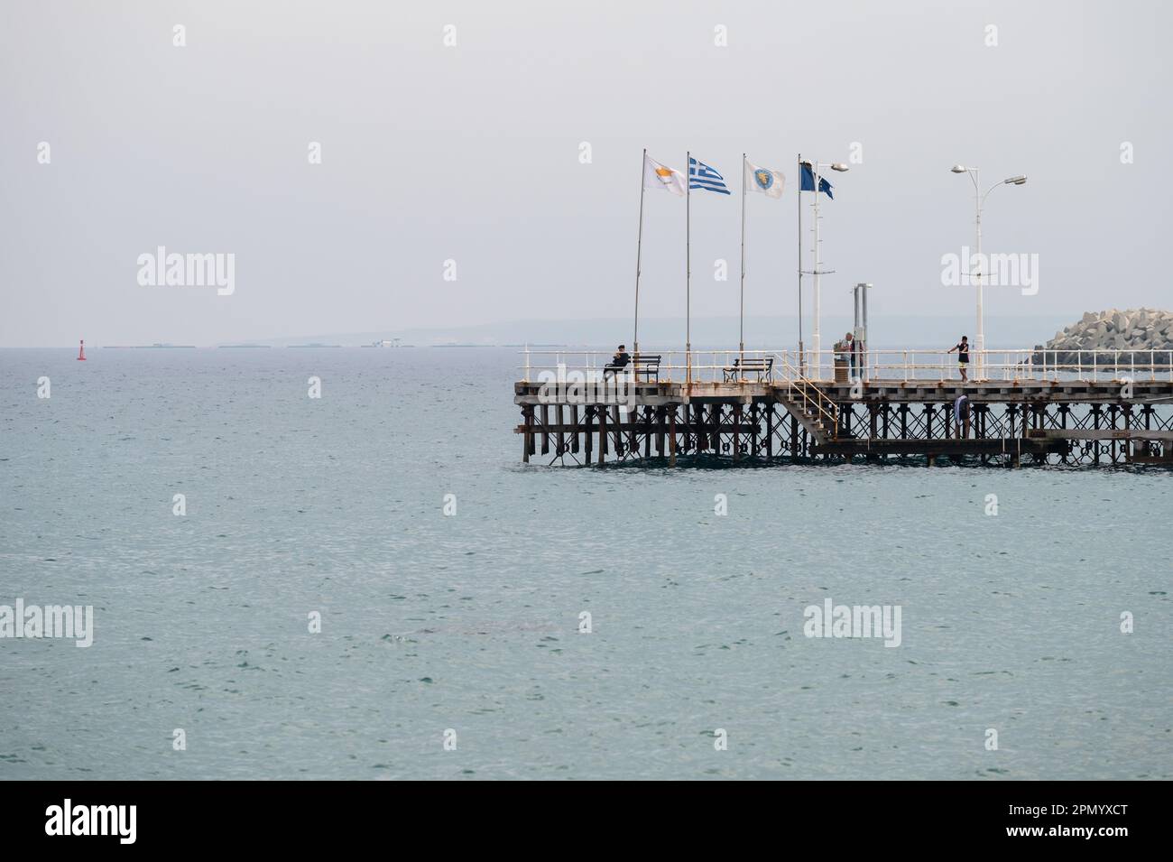 Limassol, Cyprus - March 23, 2023 - Wooden pier in the mediterranean sea with Greek, Cypriot and  European flags Stock Photo