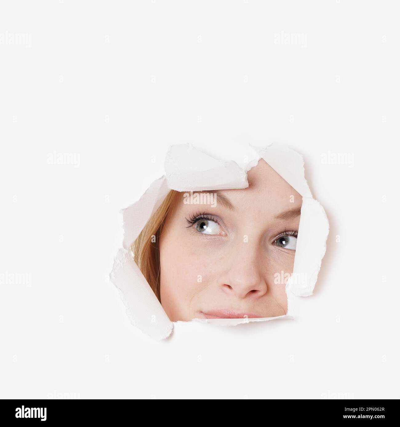 curious young woman peeking through hole and looking up Stock Photo