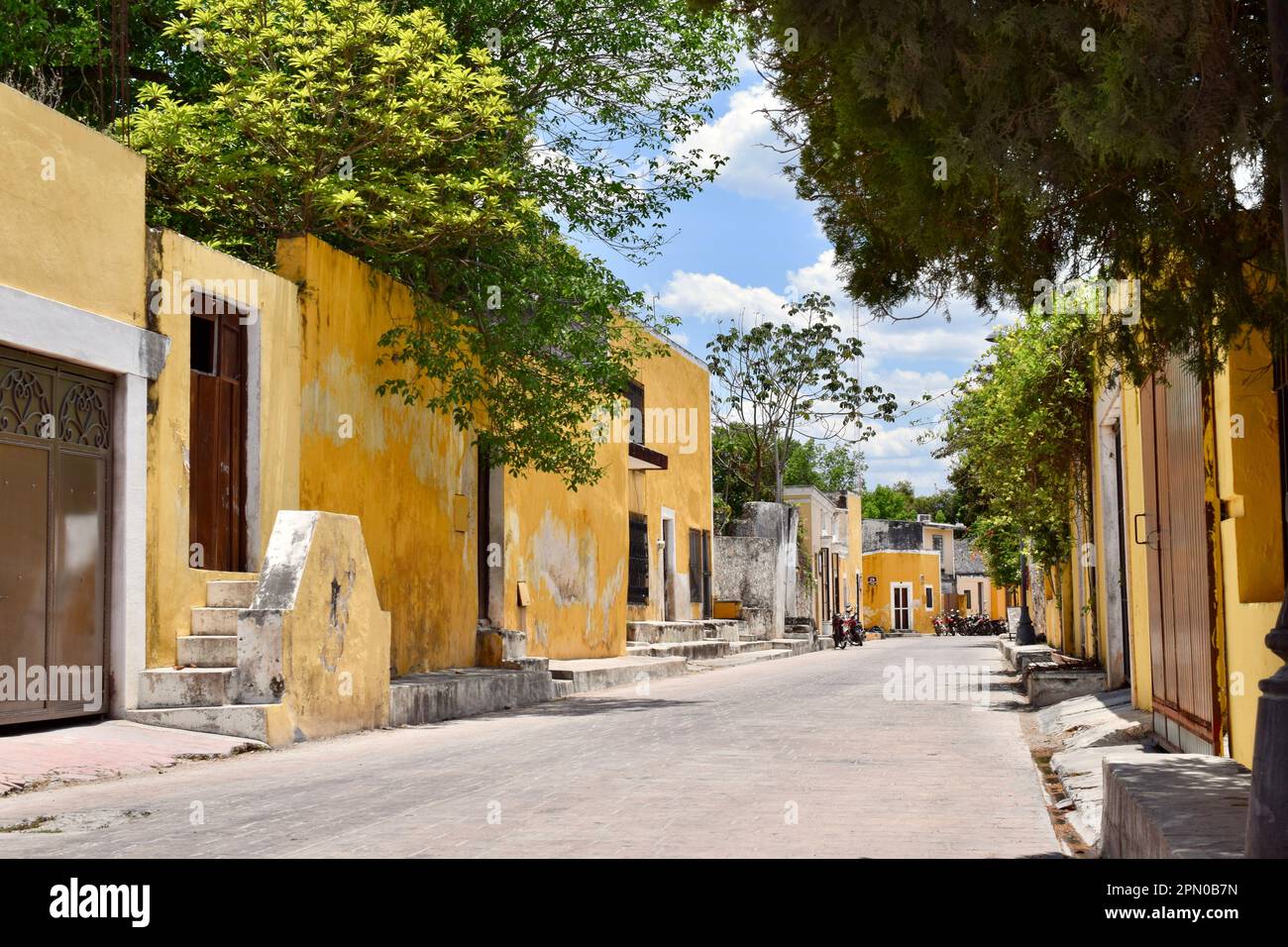 A horizontal shot of a cute side street in the yellow city of Izamal, Yucatan, Mexico. Stock Photo