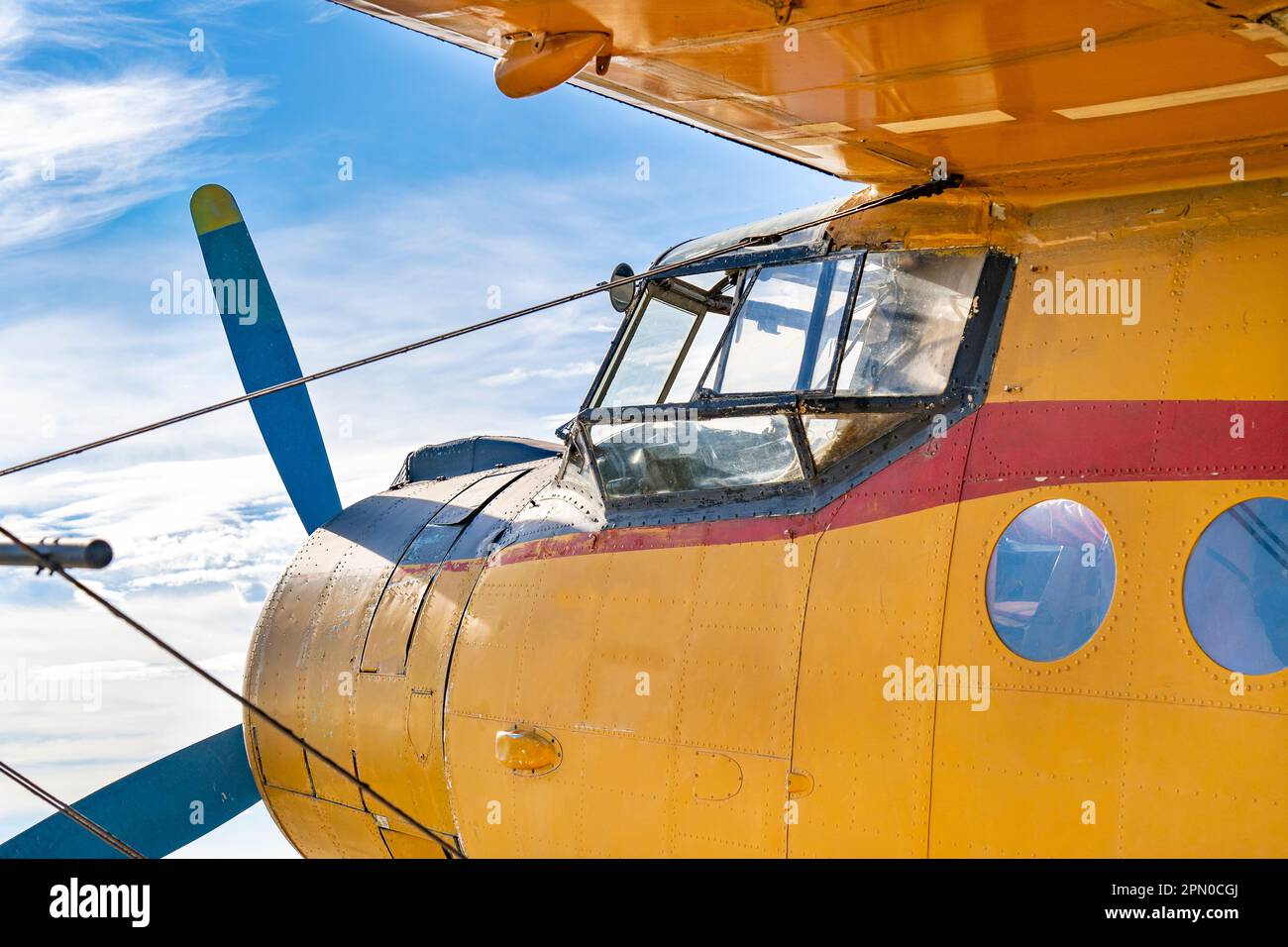 Cockpit of an old yellow-painted airplane with the blue sky in the background Stock Photo