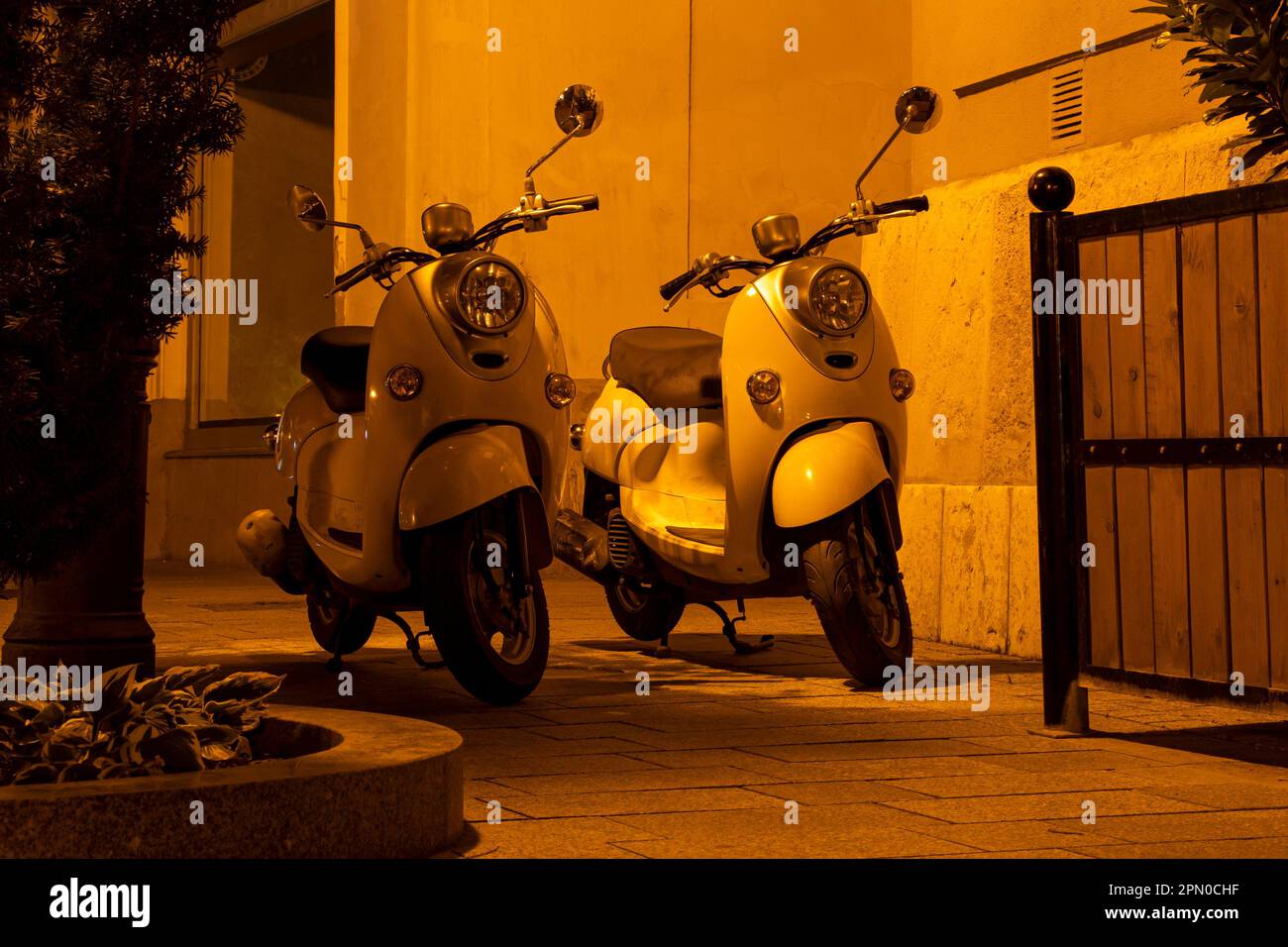 Two classic retro scooters on the street at night in yellowish lamplight Stock Photo