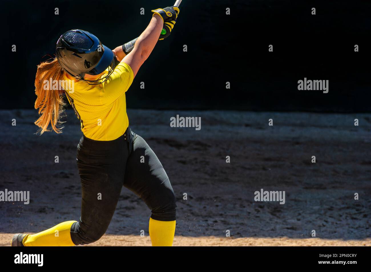 A Baseball Softball Player Is Swinging And Hitting The Ball Stock Photo