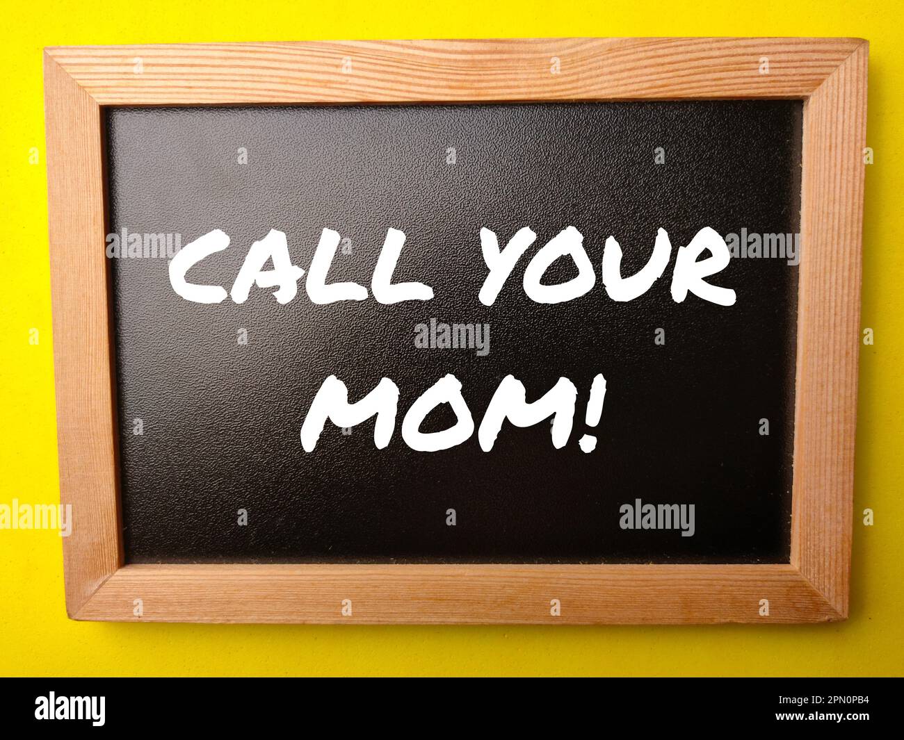 Wooden black board with the word CALL YOUR MOM on yellow background