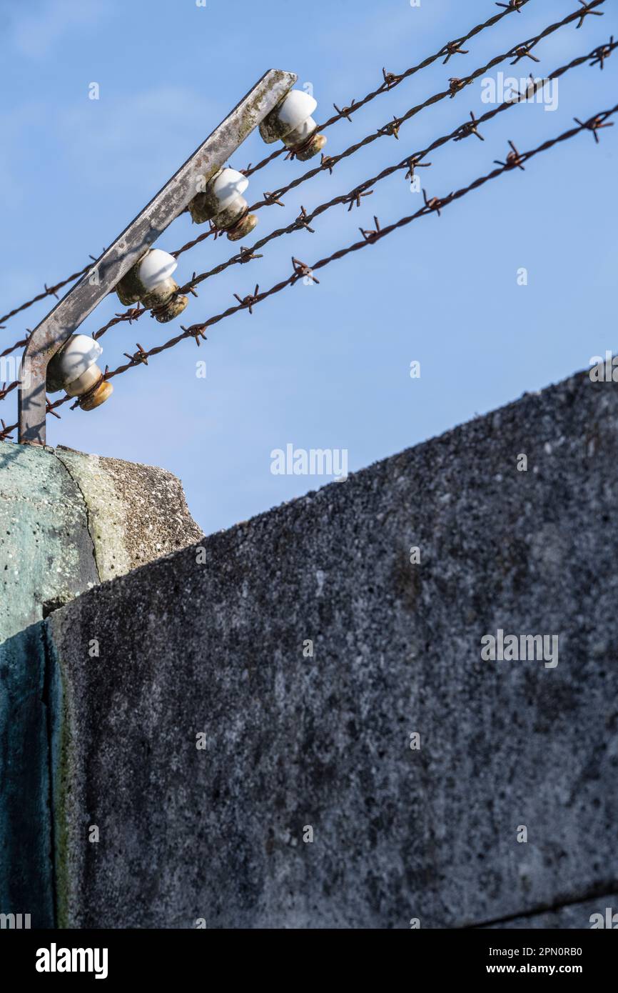 electrified barbed-wire fence above the concrete wall at the Dachau Concentration Camp Stock Photo