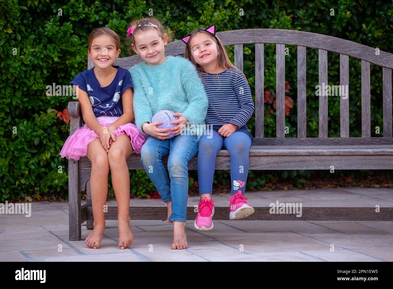 Three young girl friends on a bench Stock Photo