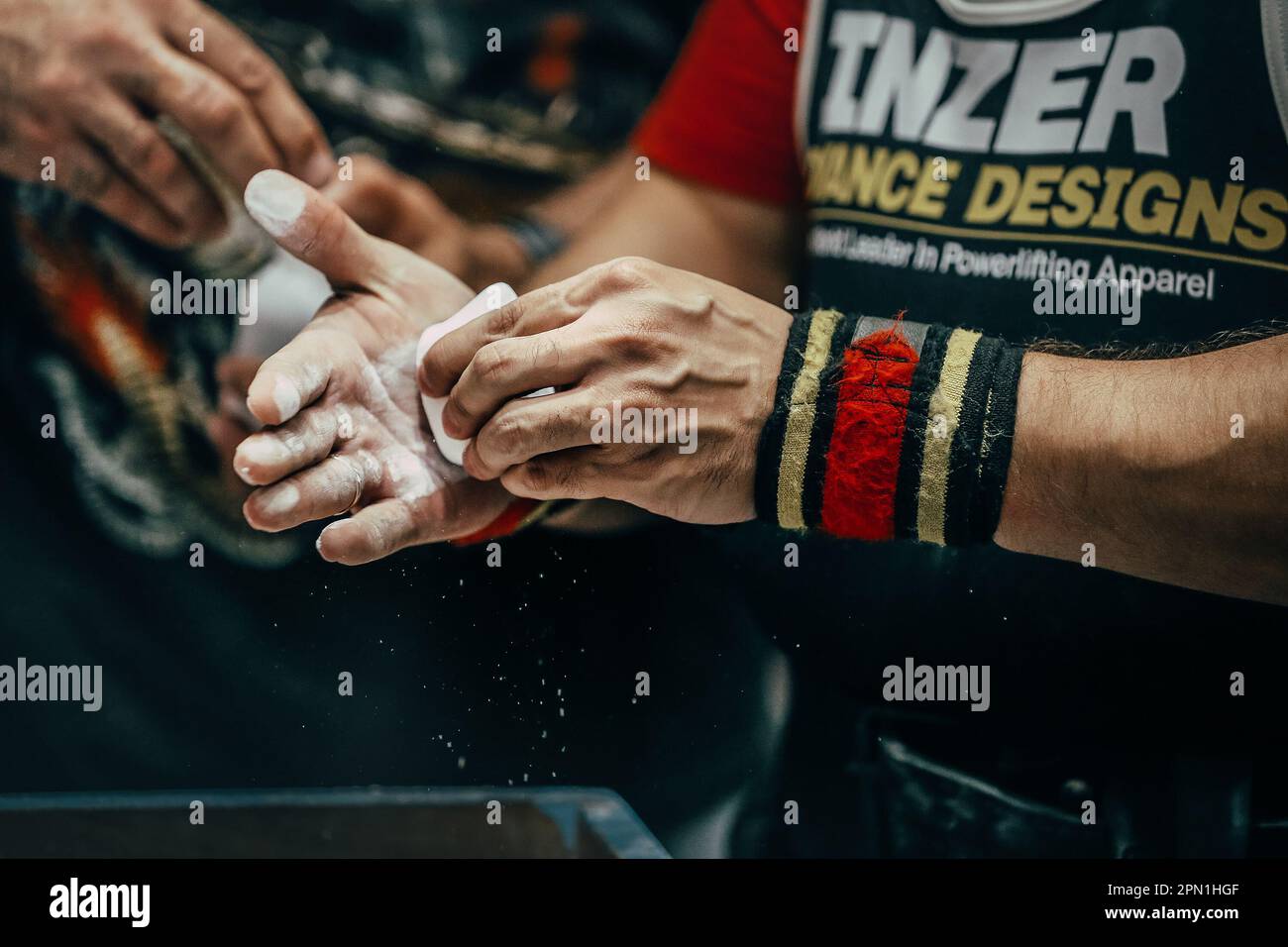 athlete powerlifter apply gym chalk on his hands for bench press. Singlet and wrist wraps Inzer