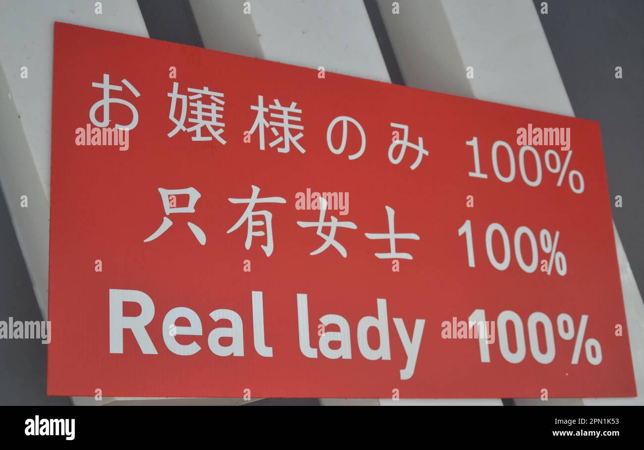 A sign outside a Bangkok, Thailand women go go bar advertises 'real lady 100%' in English and other languages. The implication is that none of the models on stage here are ladyboys, transvestites or transsexuals. Stock Photo