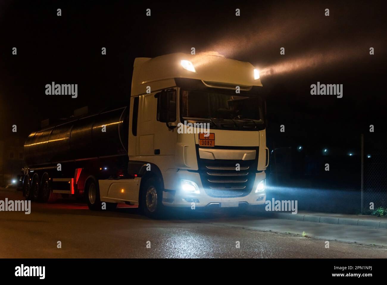 Tanker truck with dangerous goods on a foggy night with high beam lights on. Closeup Stock
