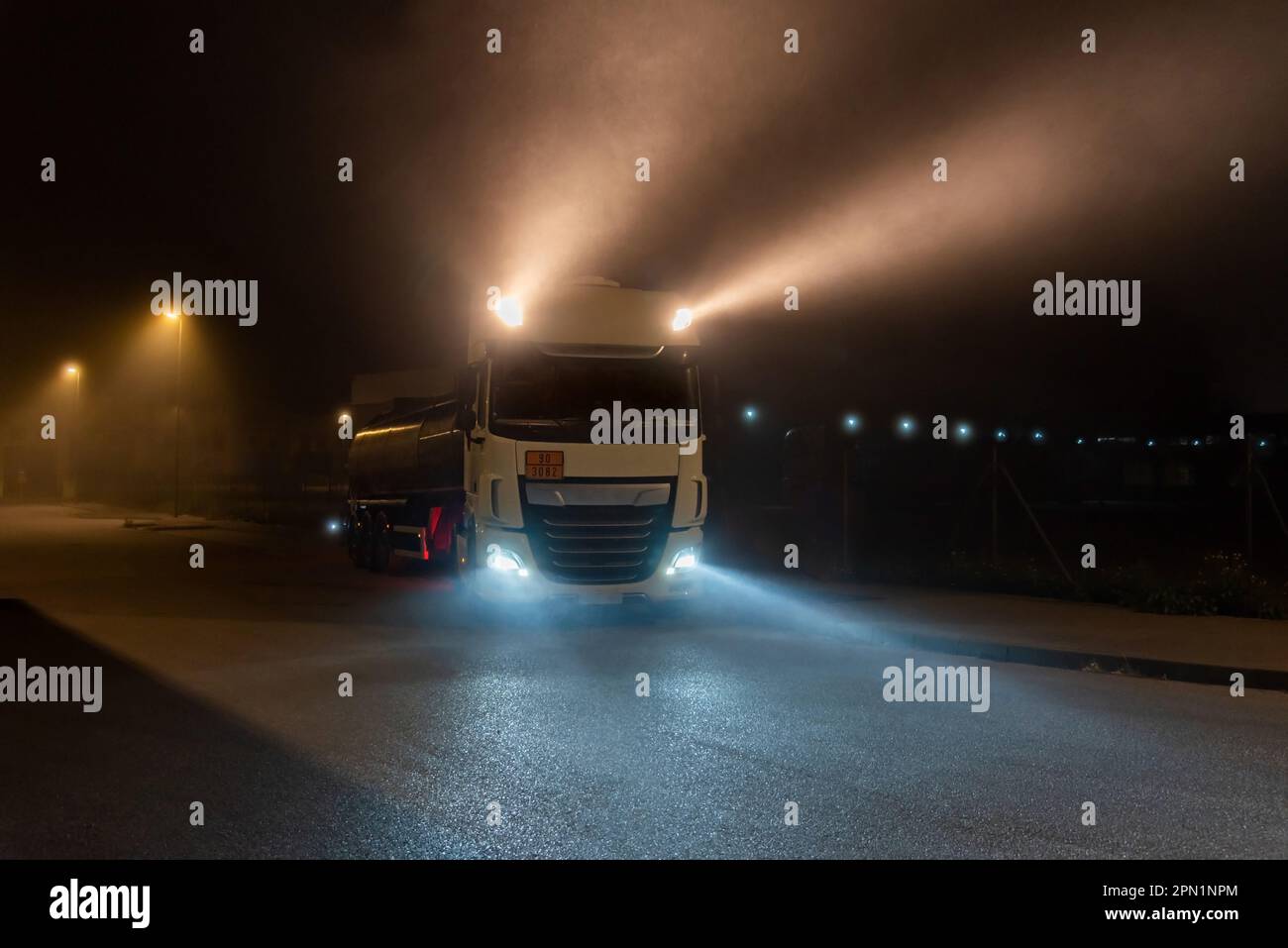 Tanker truck with dangerous goods on a foggy night with high beam lights on. Closeup Stock