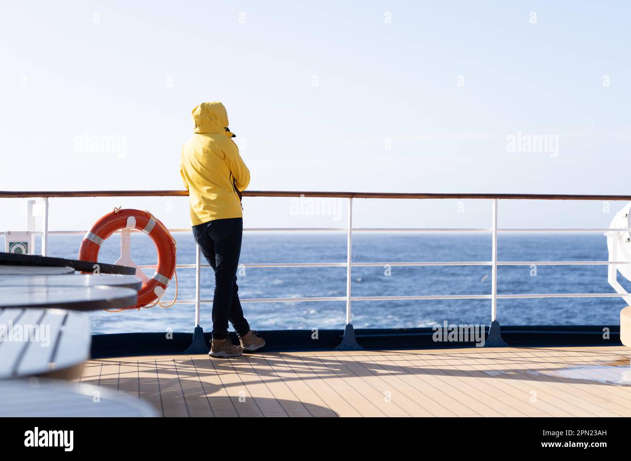 2 cruise passengers  stands at the railing at the stern of a cruise ship and looks back at the blue open sea. Stock Photo