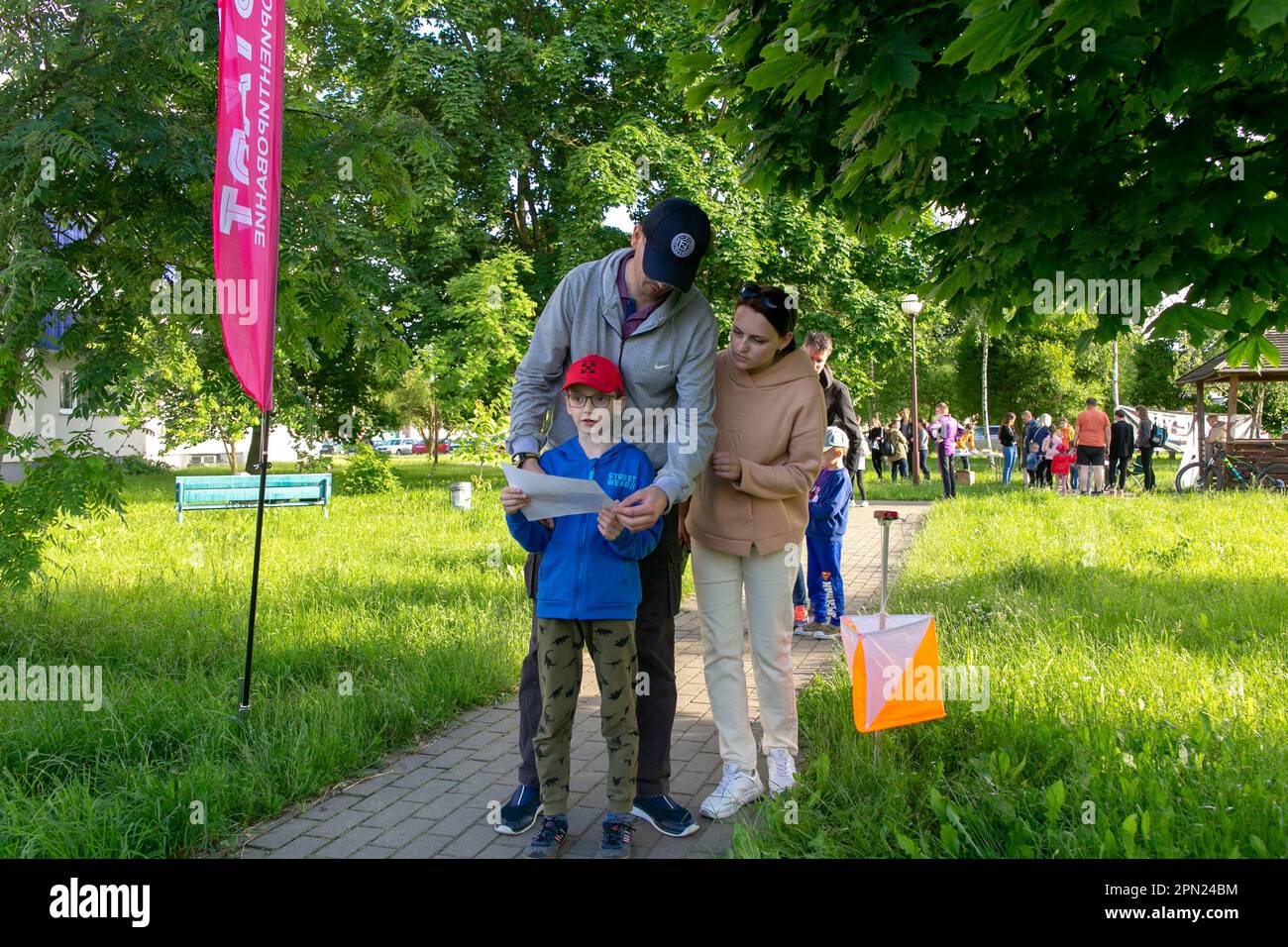 Grodno, Belarus - 15 June, 2022: Training of the Veras orienteering club . A young family of three people at the start of the route check the map and Stock Photo