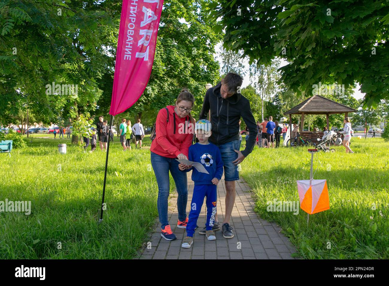 Grodno, Belarus - 15 June, 2022: Training of the Veras orienteering club . A young family of three people at the start of the route check the map and Stock Photo