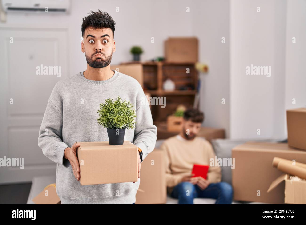 Homosexual couple moving to a new home puffing cheeks with funny face ...