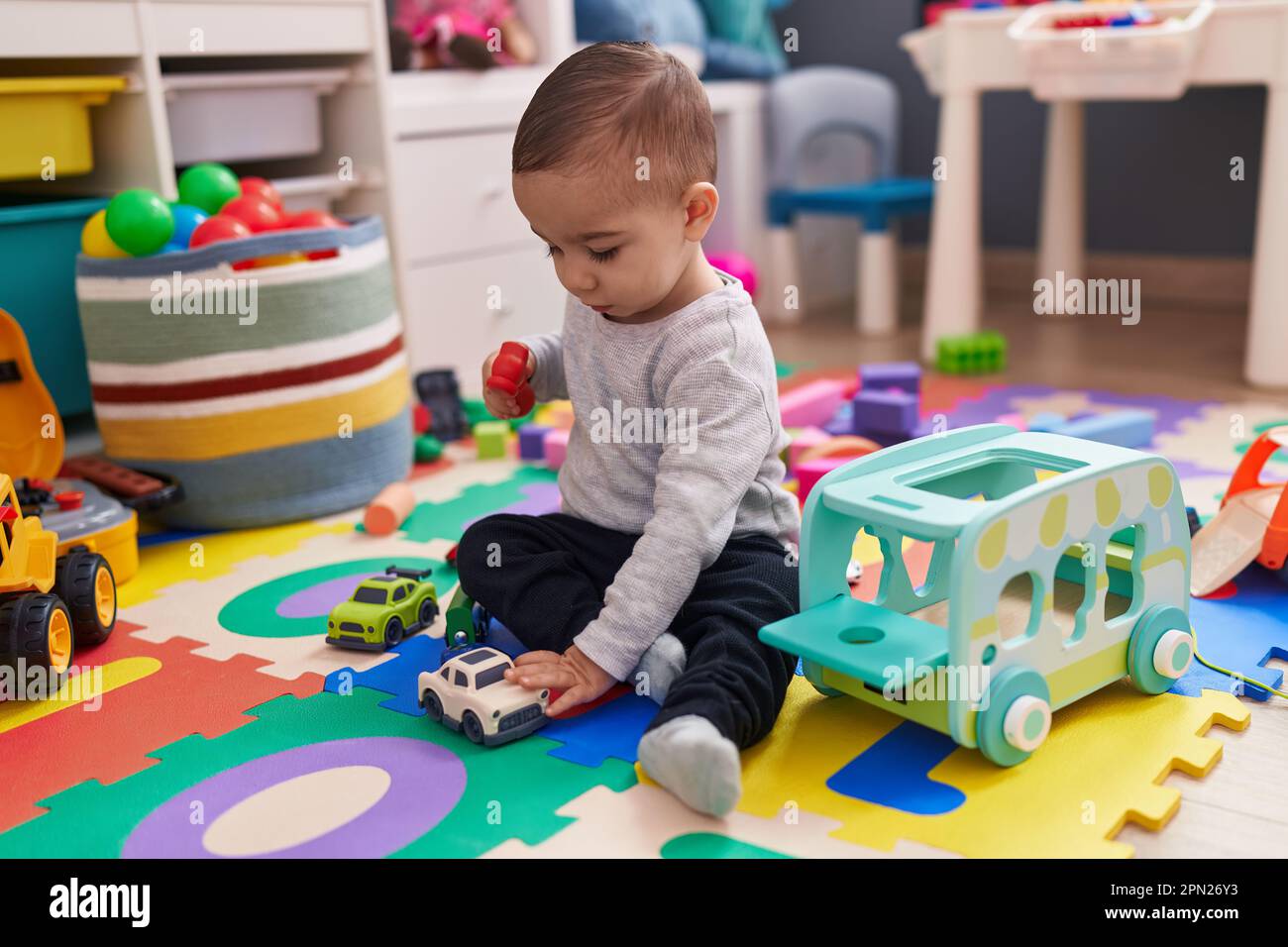 Adorable hispanic boy playing with car toy sitting on floor at ...