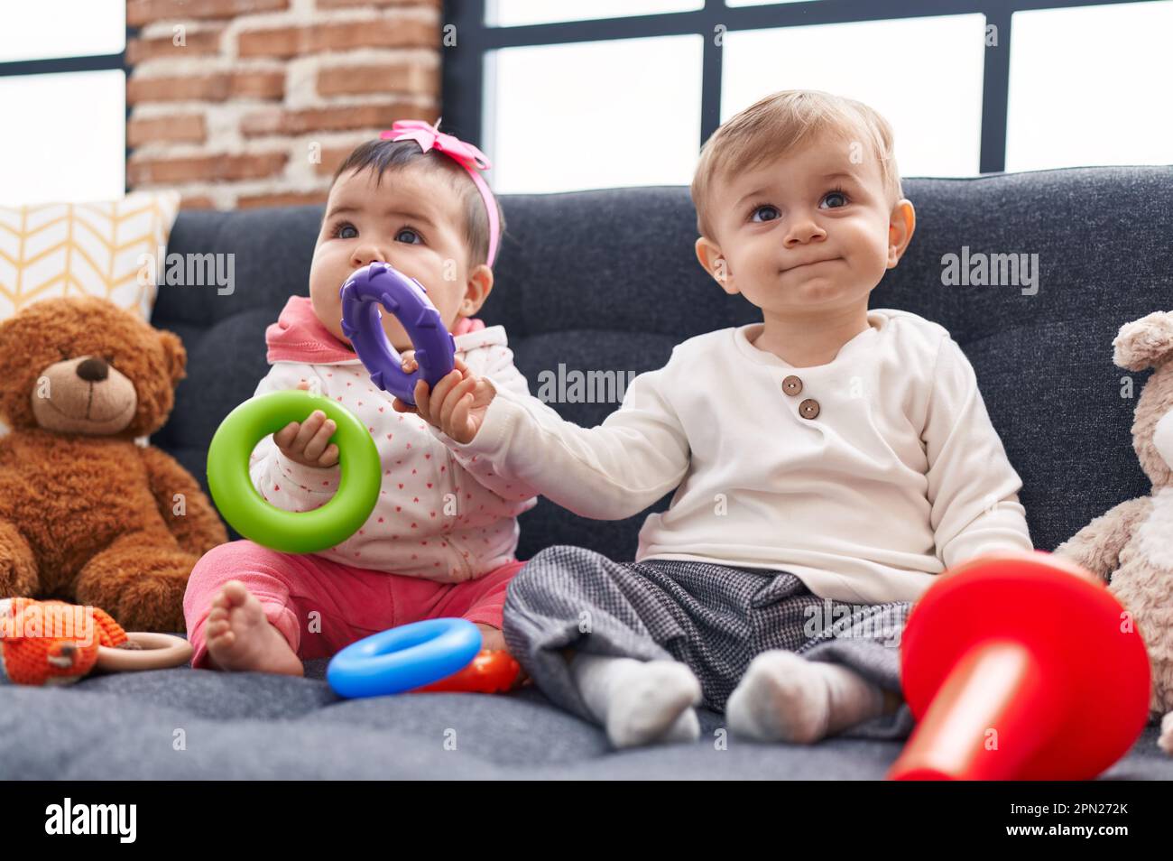 Adorable boy and girl playing with hoops game sitting on sofa at home ...