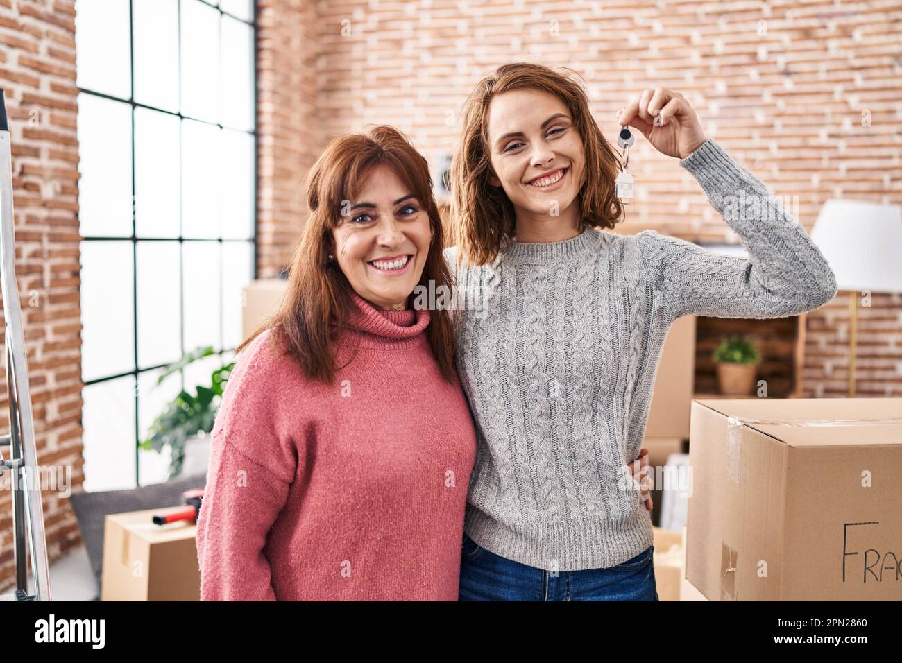 Mother and daughter moving to a new home holding keys looking positive ...