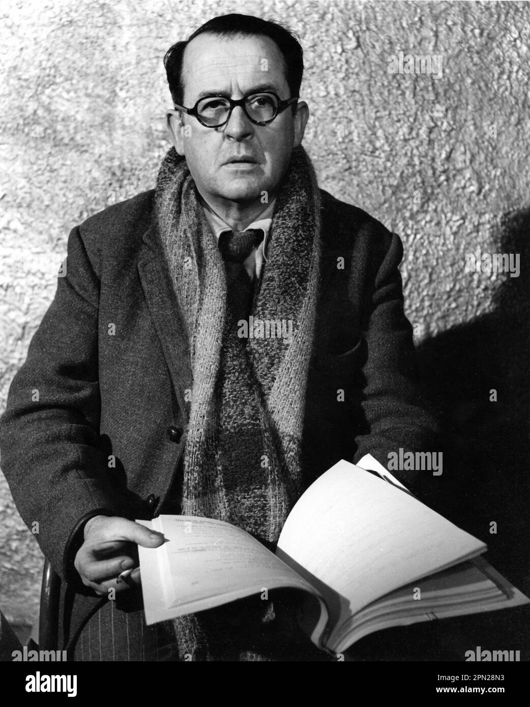 Director ALBERTO CAVALCANTI on set candid portrait with script circa 1945 around time he directed the celebrated Ventriloquist's Dummy story with Michael Redgrave in the anthology film DEAD OF NIGHT 1945 directors ALBERTO CAVALCANTI CHARLES CRICHTON BASIL DEARDEN and ROBERT HAMER music Georges Auric producer Michael Balcon Ealing Studios / Eagle - Lion Distributors Limited Stock Photo