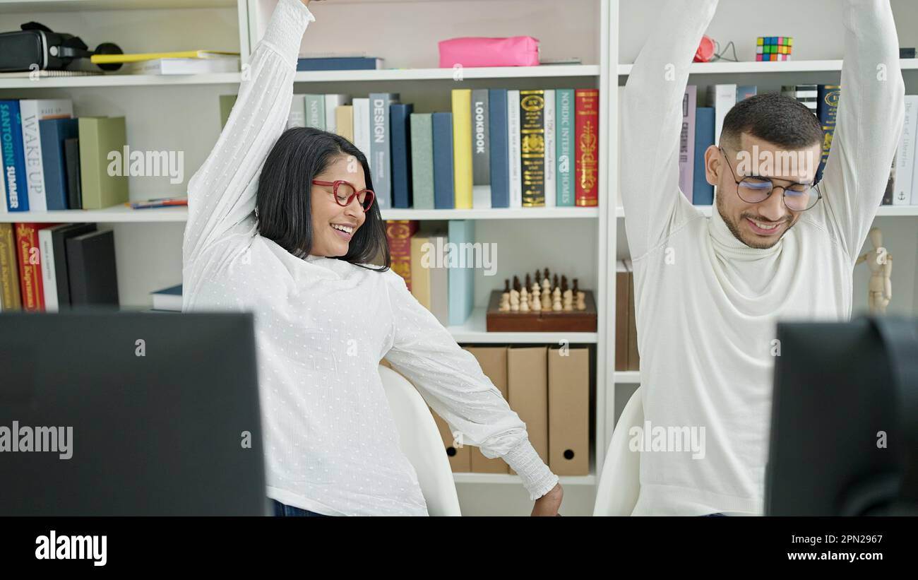 Man and woman students using computer stretching arms at university ...