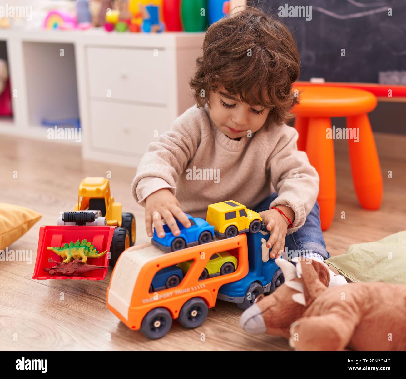 Adorable hispanic boy playing with car toy sitting on floor at ...