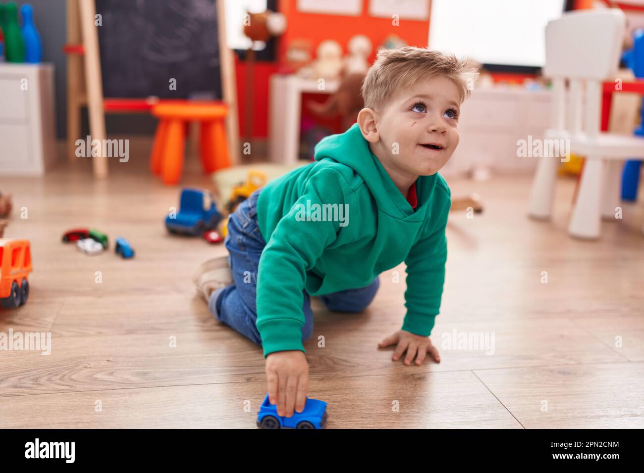 Adorable caucasian boy playing with car toy sitting on floor at ...