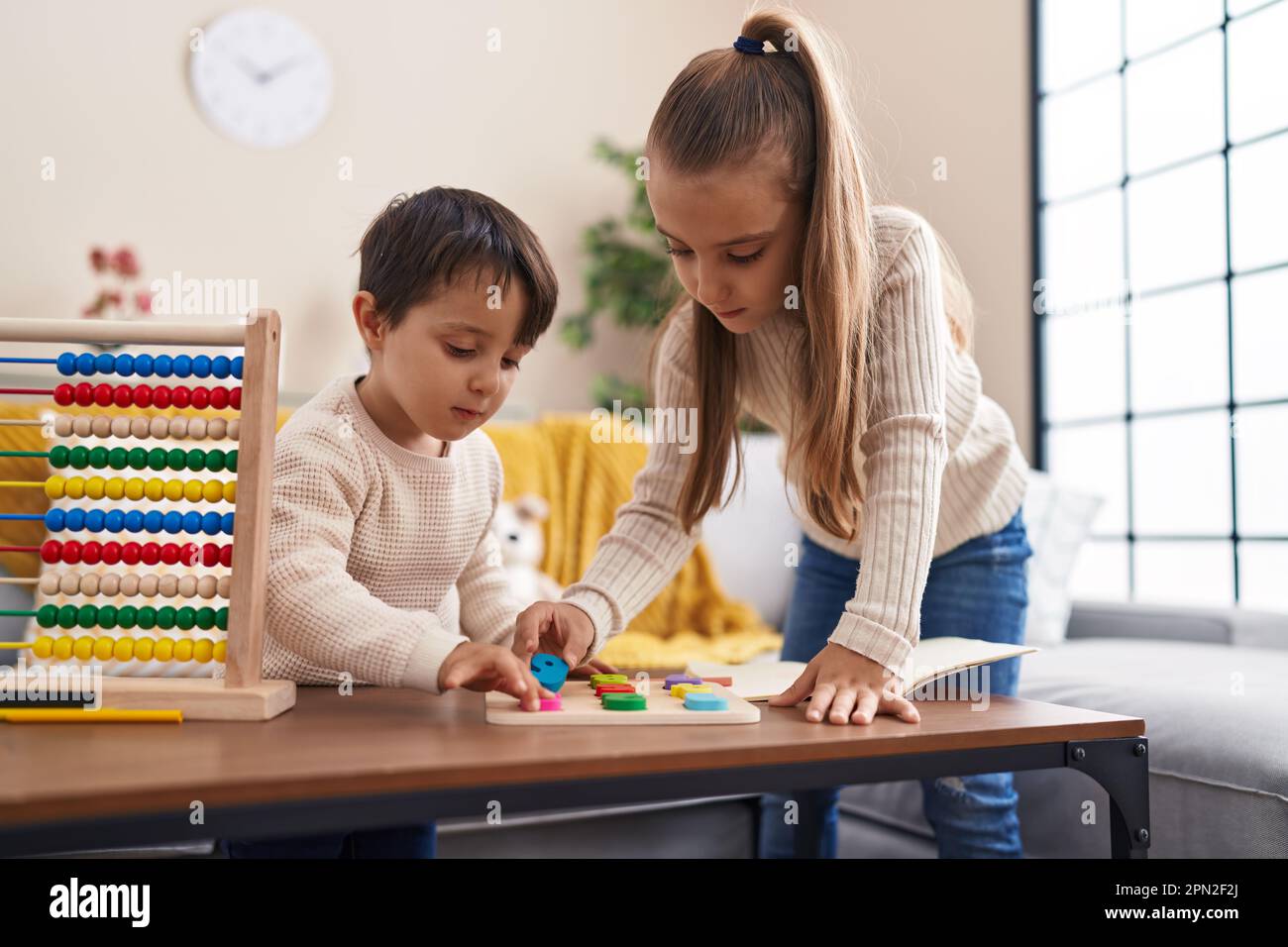 Children Playing Math On Computer Adorable boy and girl playing with maths puzzle game standing at home ...