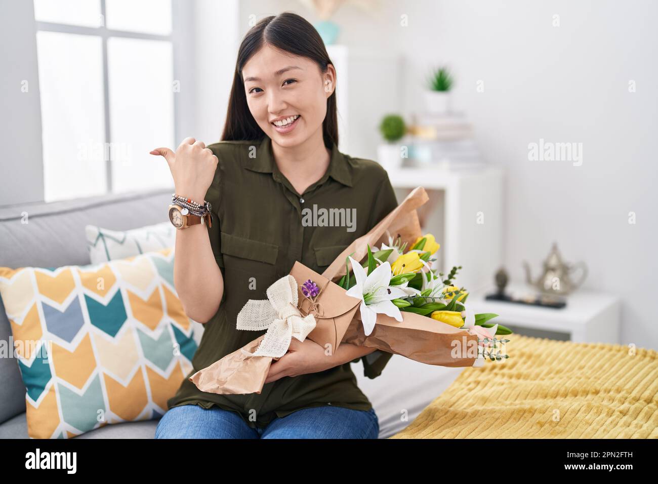 Chinese young woman holding bouquet of white flowers pointing to the ...