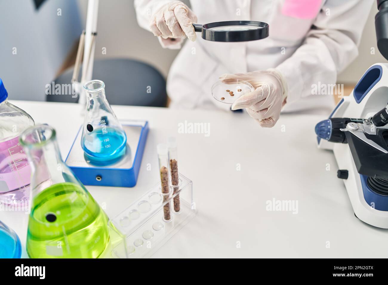 Young chinese woman wearing scientist uniform using loupe at laboratory