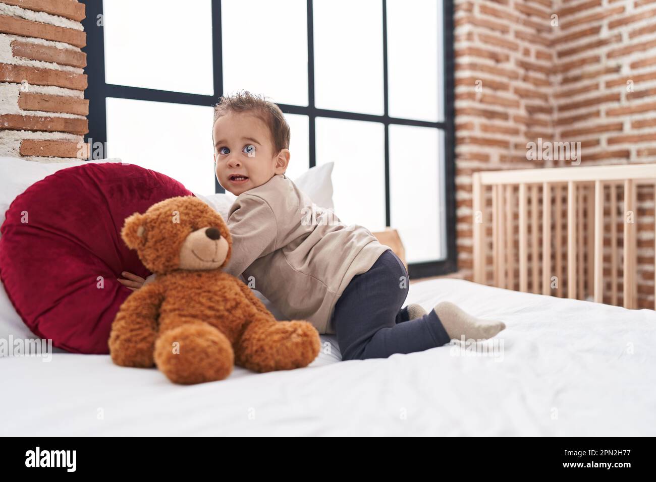 Adorable hispanic boy sitting on bed with teddy bear at bedroom Stock ...