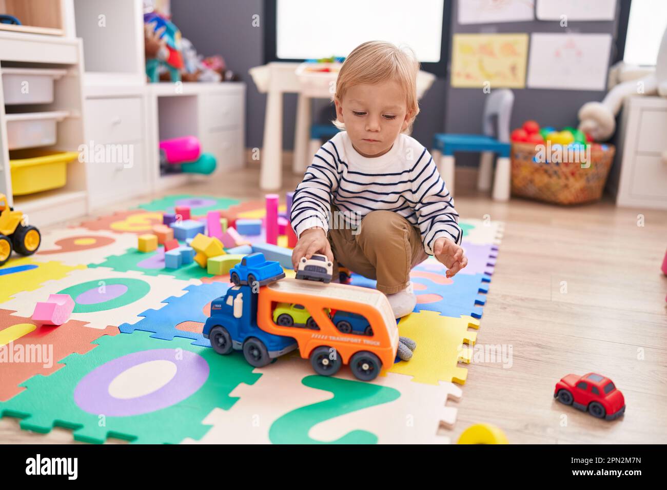 Adorable caucasian boy playing with car toy sitting on floor at ...
