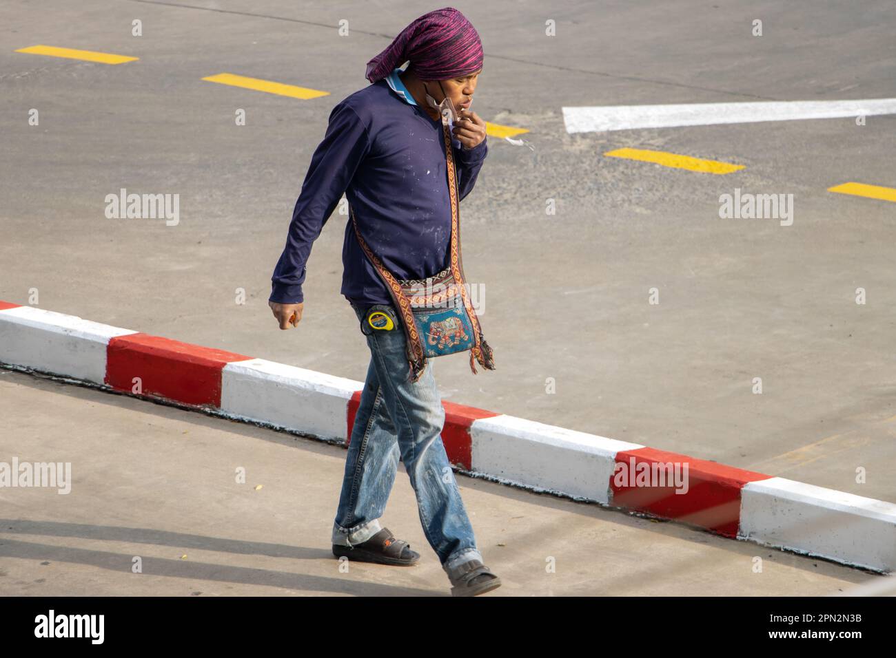 SAMUT PRAKAN, THAILAND, JAN 30 2023, A man walks down the street and spits on the ground Stock Photo