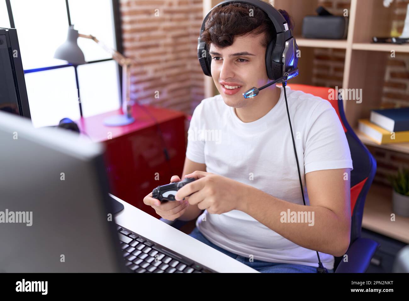 Non binary man streamer playing video game using joystick at gaming ...