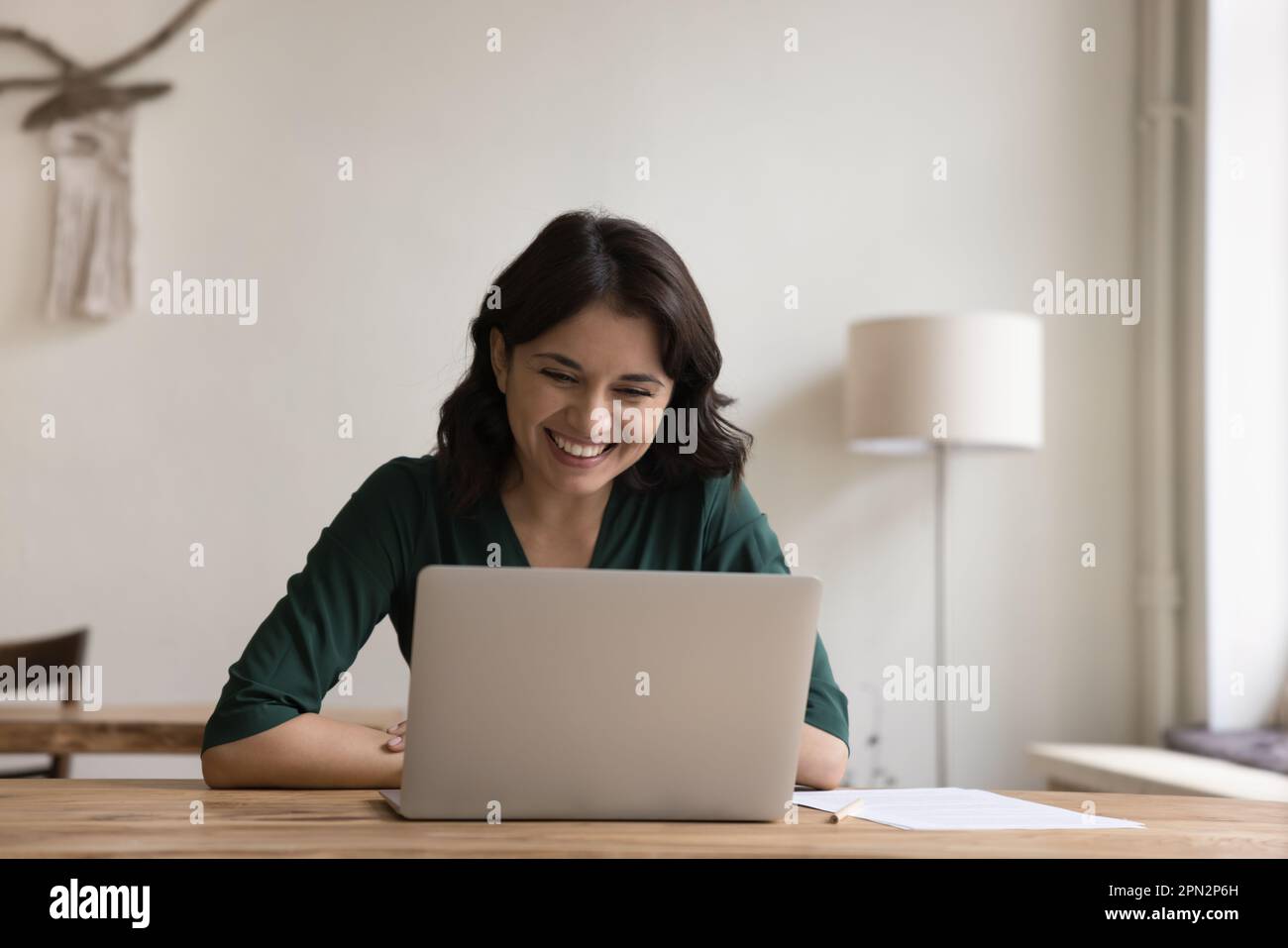 Happy Armenian female freelance doing telework using laptop Stock Photo