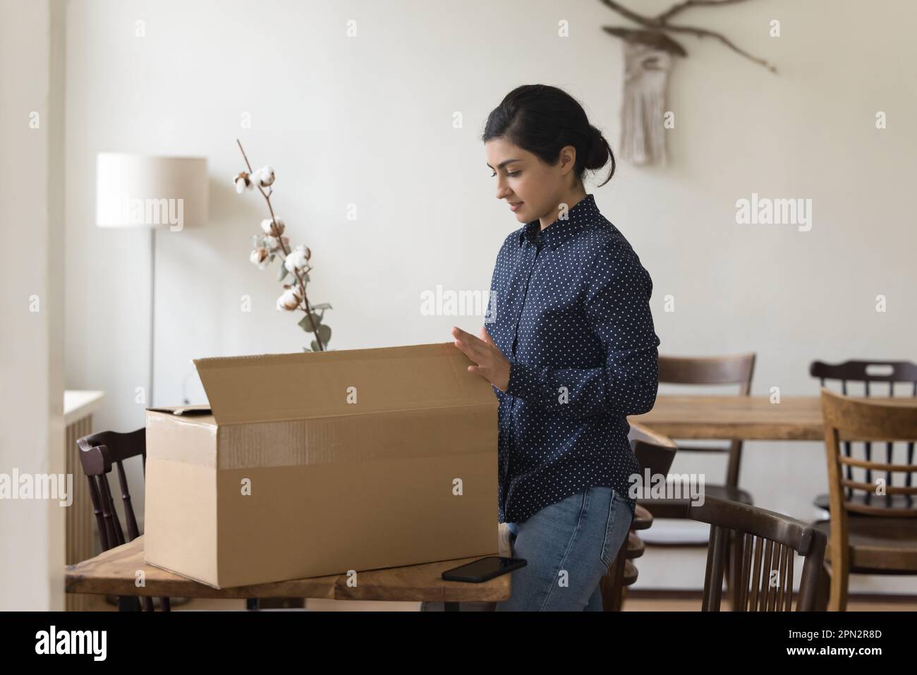 Indian woman get parcel, open box to review received goods Stock Photo