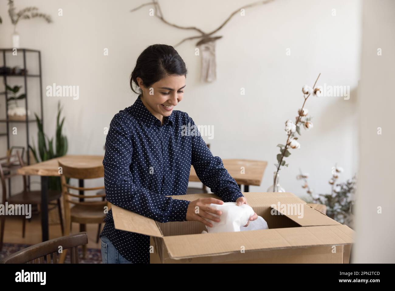 Indian woman opens parcel feels satisfied with good online shopping Stock Photo
