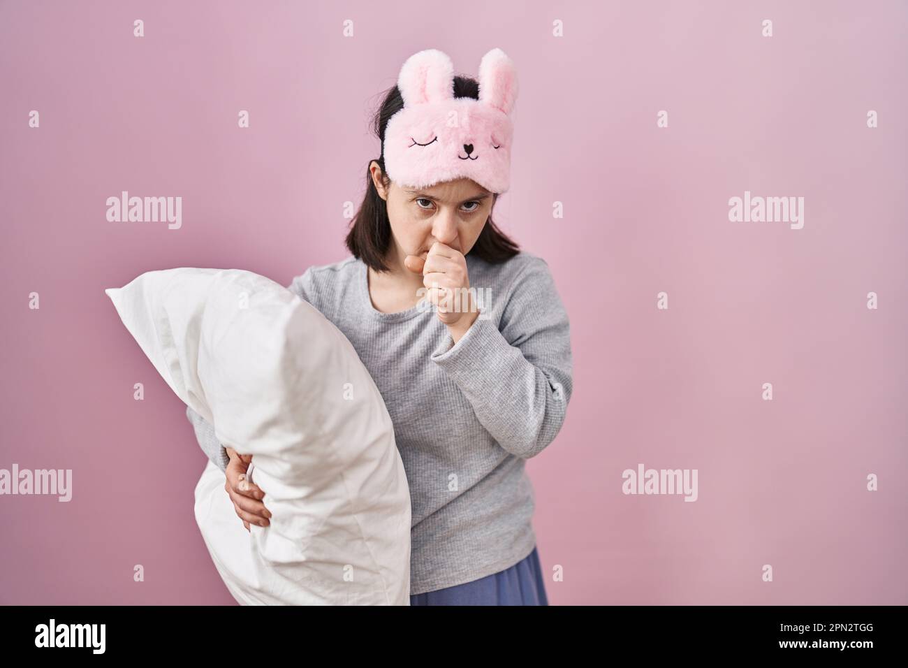 Woman with down syndrome wearing sleeping mask hugging pillow feeling