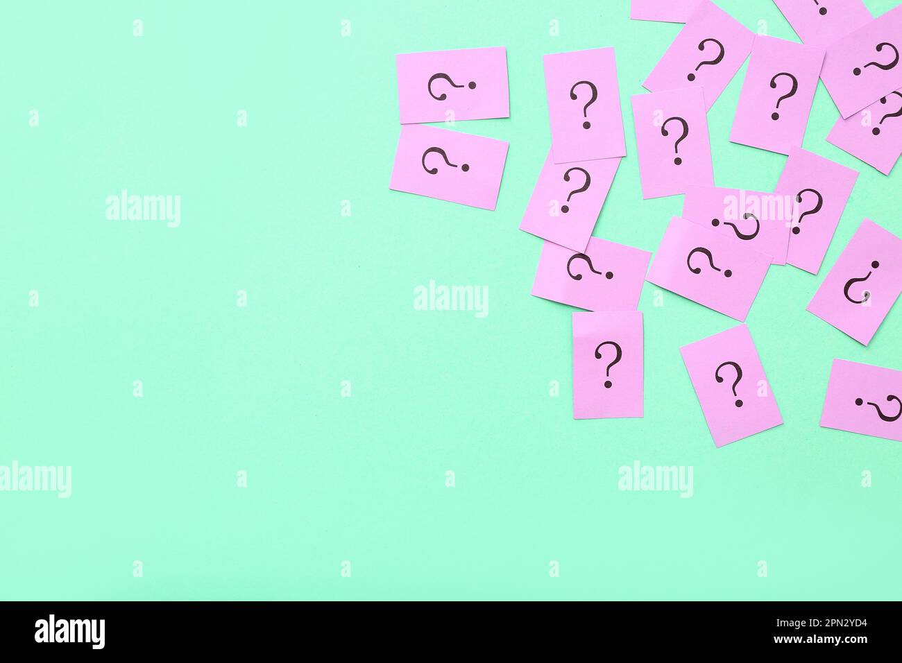 Papers with question marks on green background Stock Photo - Alamy