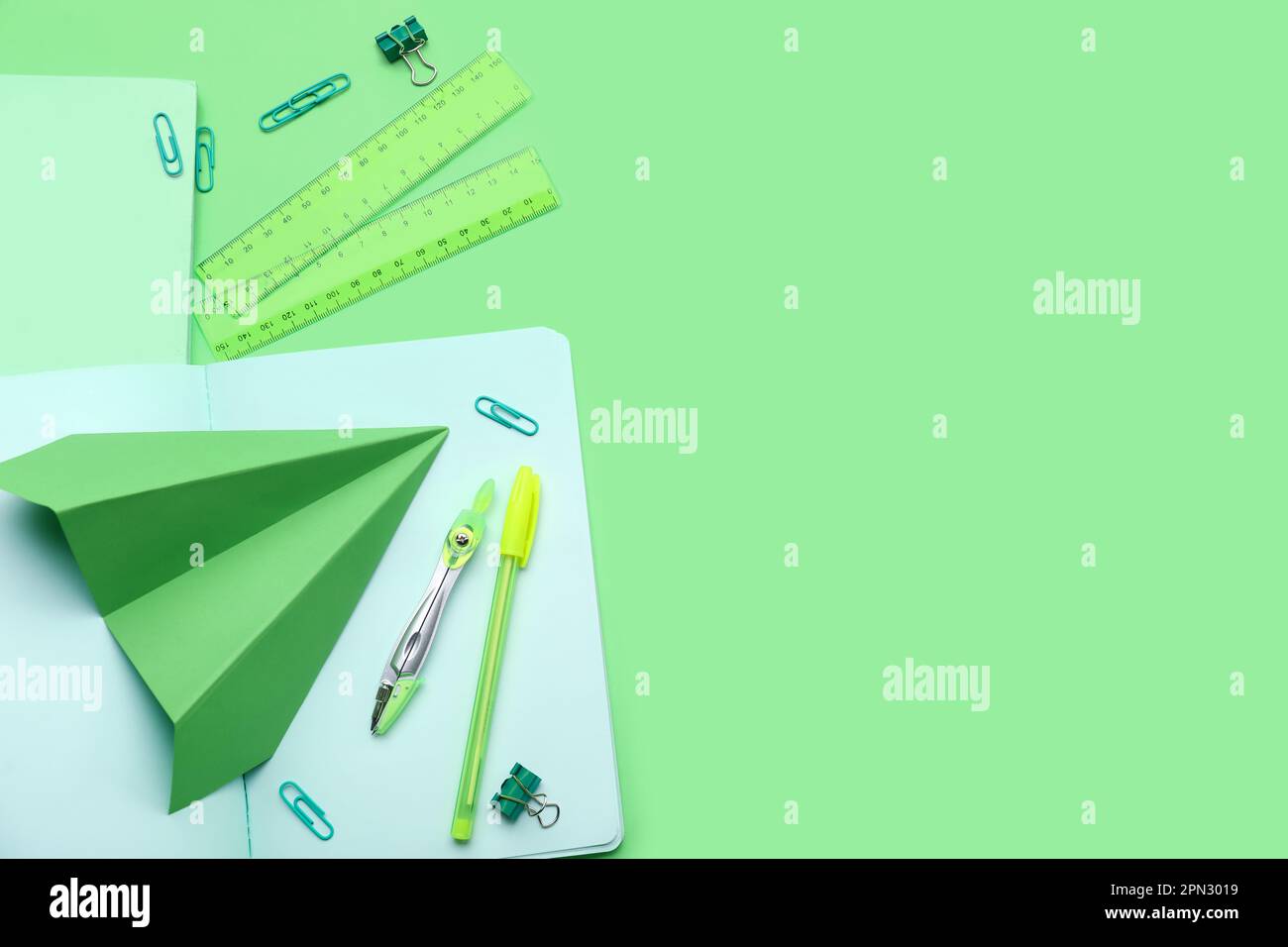 Composition with stationery supplies and paper plane on green ...