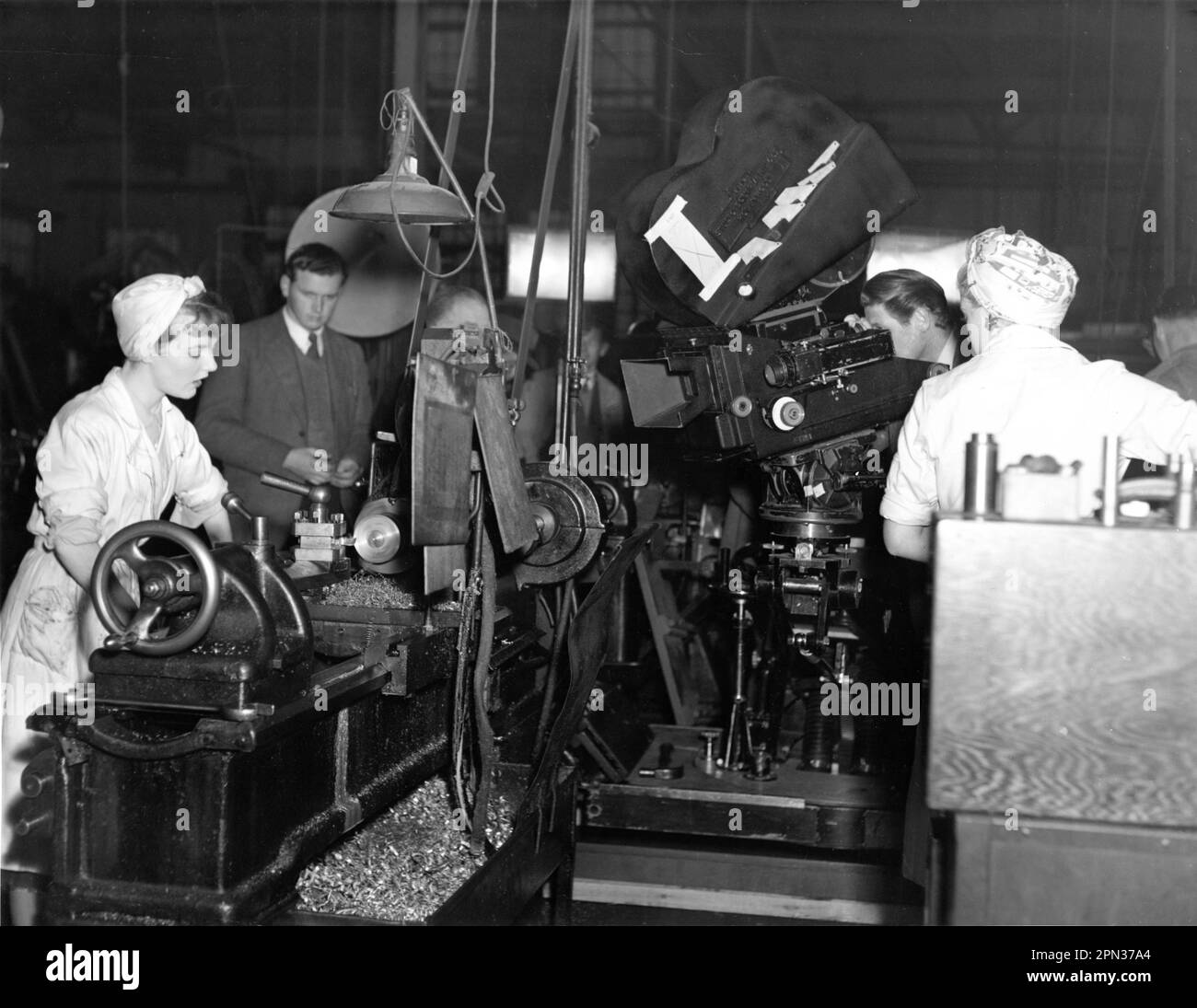 PETULA CLARK and DIANA DORS (back to camera) as factory girls on set candid with Film Crew during filming of DANCE HALL 1950 director CHARLES CRICHTON original screenplay E.V.H. Emmett Diana Morgan and Alexander Mackendrick cinematographer Douglas Slocombe art direction Norman G. Arnold producer Michael Balcon Ealing Studios / Stock Photo