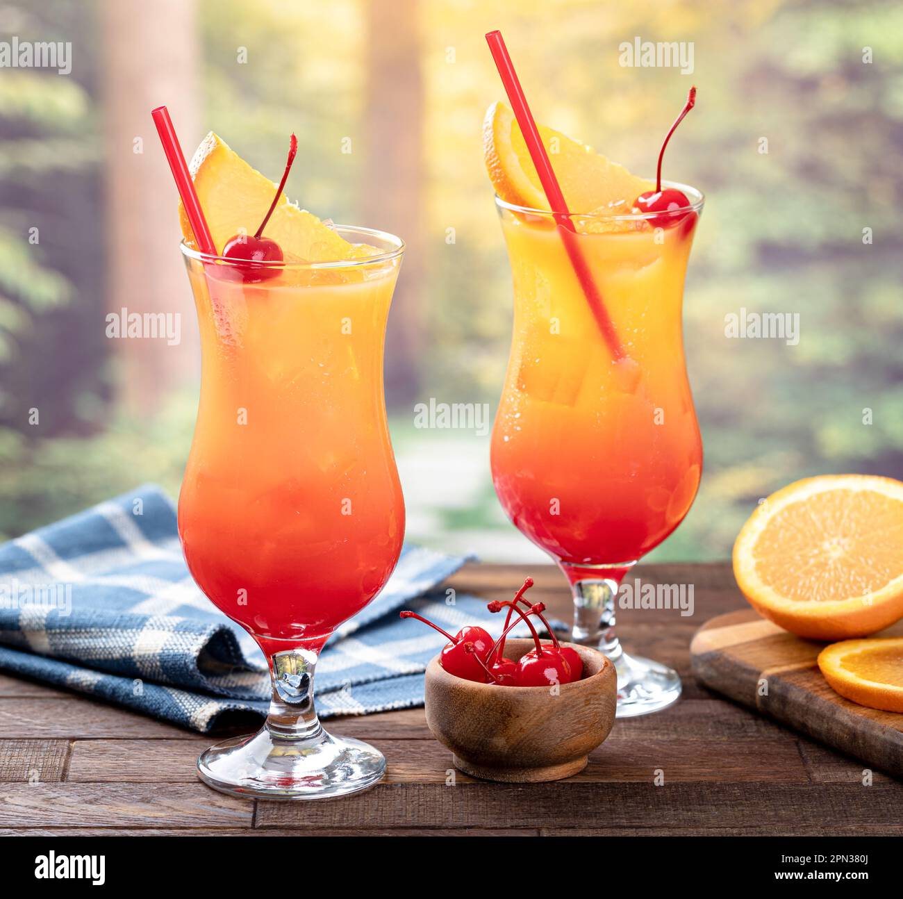 Tequila sunrise cocktail with orange slice and cherry on wooden table with  summer background Stock Photo - Alamy