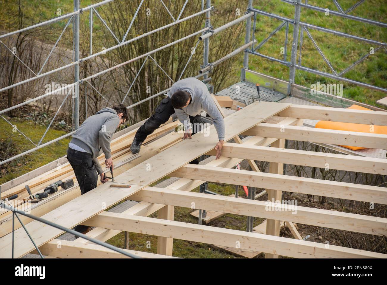 Two young carpenters building a carport. Apprentice learns from trainer. Stock Photo