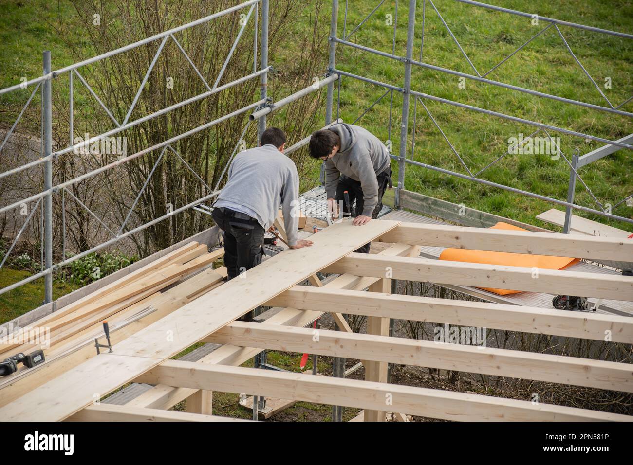 Two young carpenters building a carport. Apprentice learns from trainer. Stock Photo