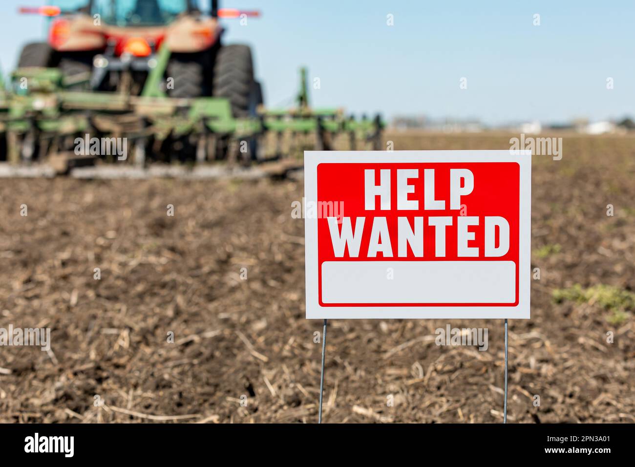 Help wanted sign in farm field during spring planting season. Farm labor shortage, agriculture job market and employment concept. Stock Photo
