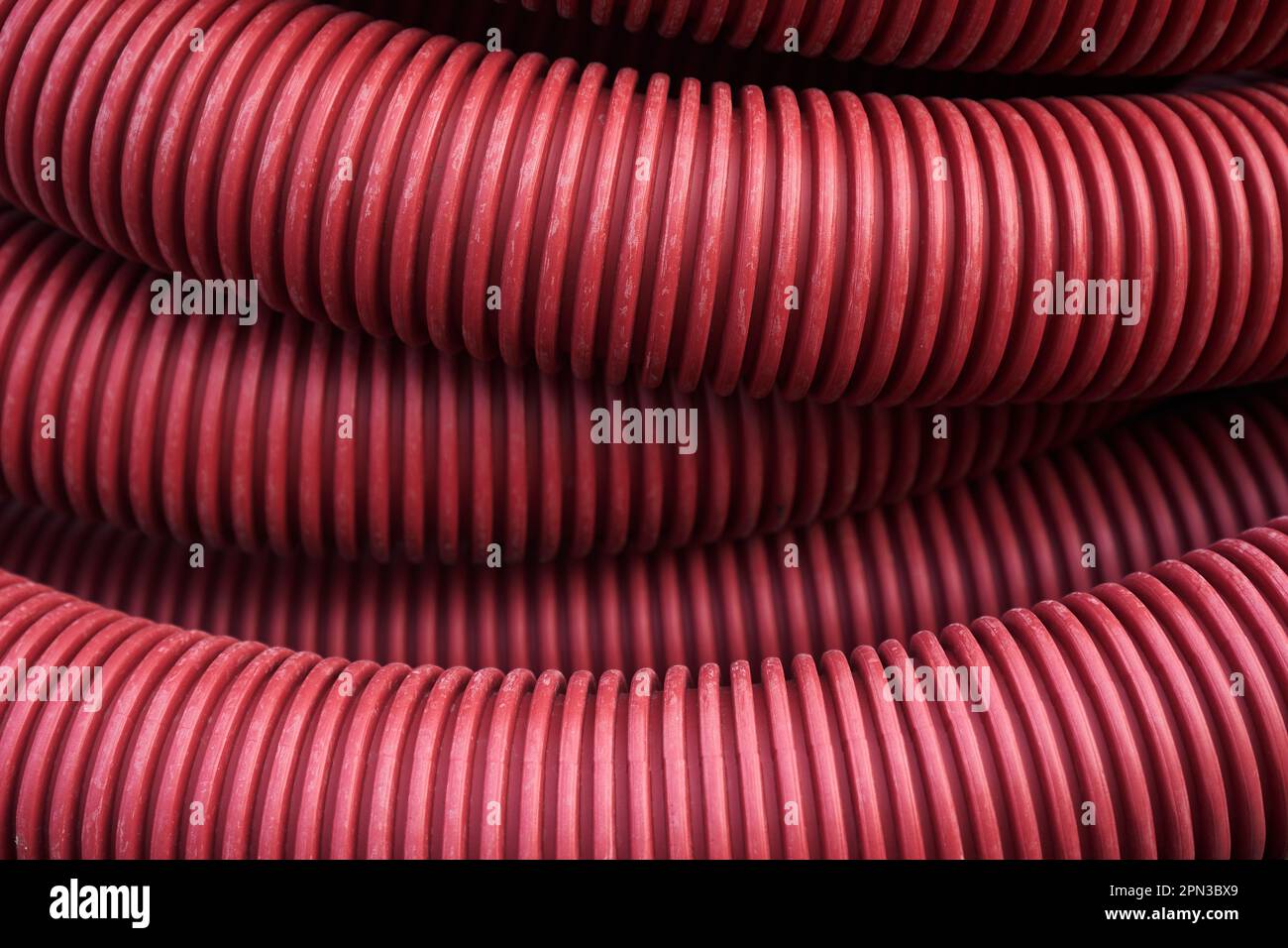 Corrugated for insulation cable of wires underground, plastic tube, electricity protection pipe for construction works, red corrugation close-up with copy space. High quality photo Stock Photo