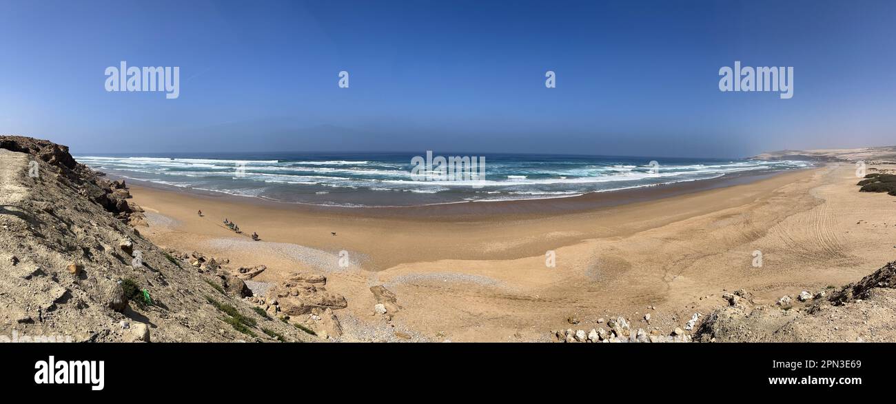 Morocco: view of Atlantic Ocean near Essaouira with some mule-driven workers crossing a beach to go and collect molluscs and shellfish from mussels Stock Photo