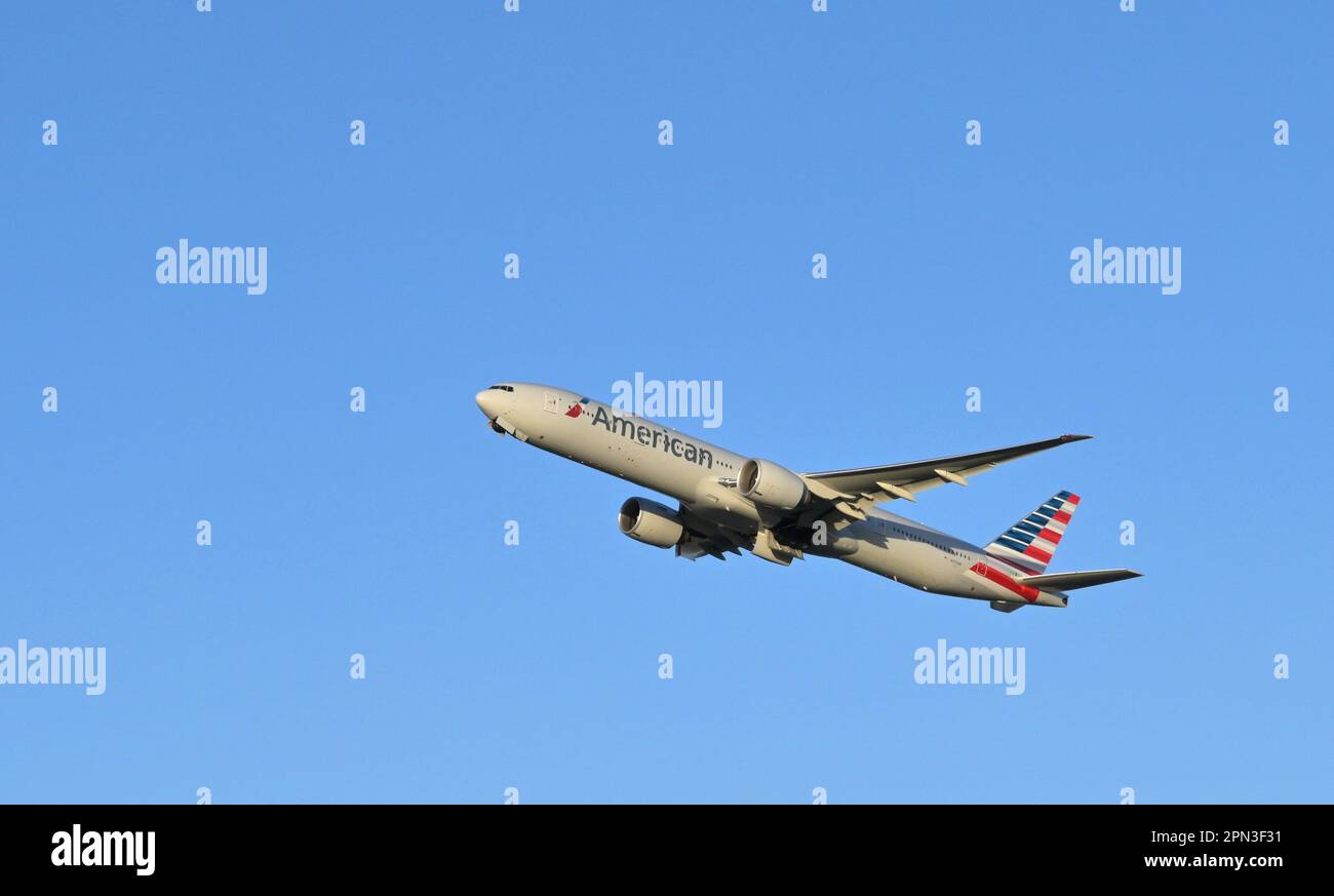 London, England - January 2023: American Airlines Boeing 777 climbing after take off from Heathrow Airport against a deep blue sky Stock Photo