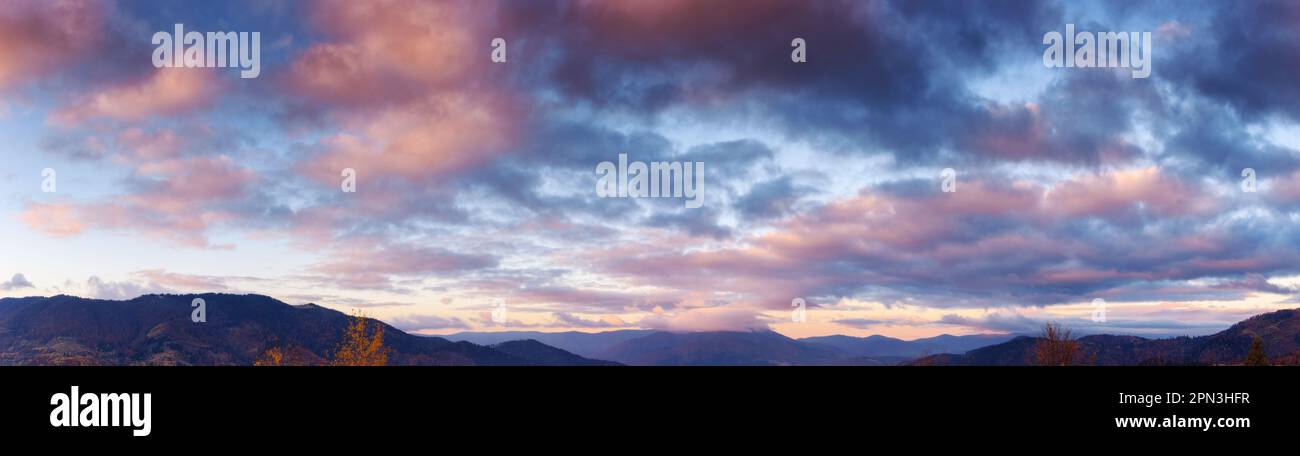 panorama of heavens at dawn. clouds in red and orange colors of a rising sun on a blue sky Stock Photo