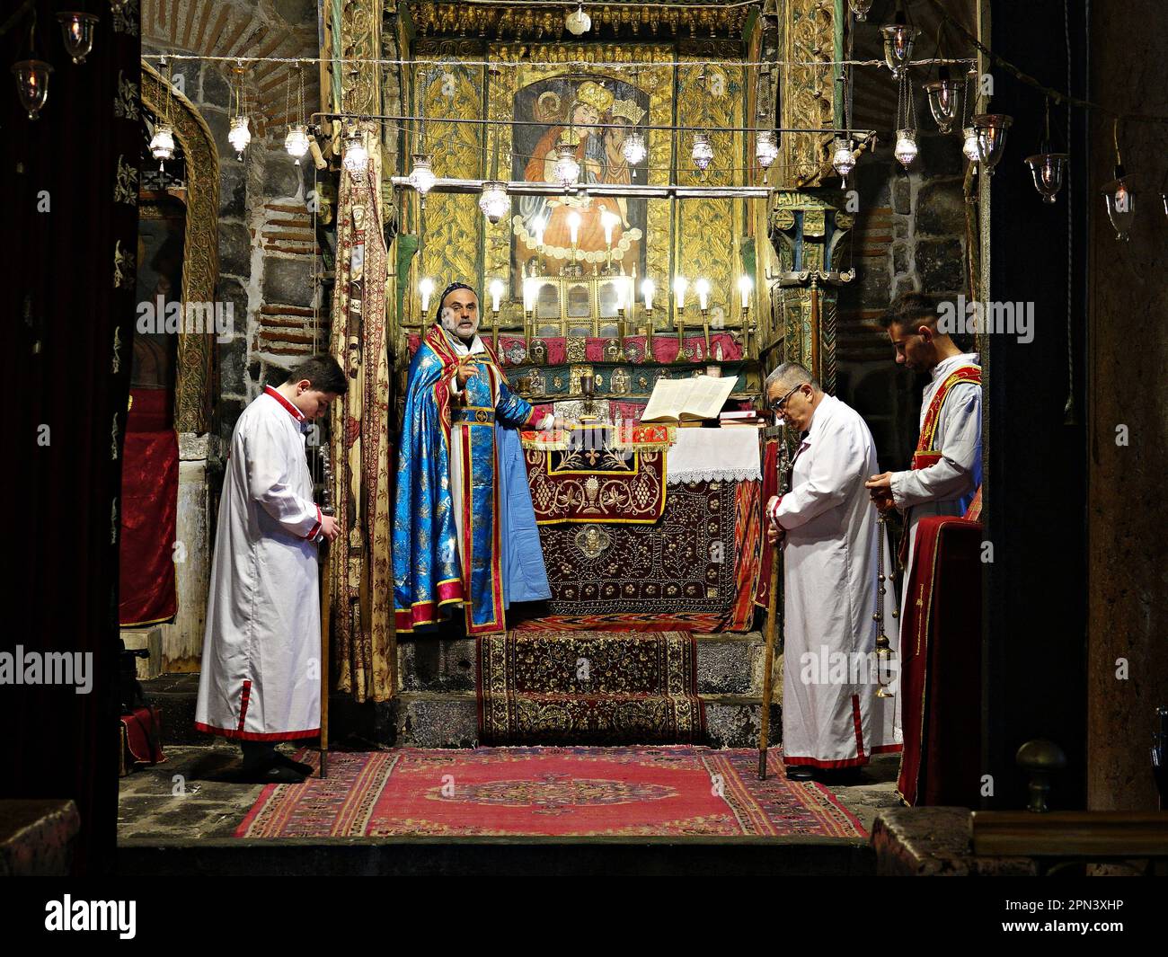 Priest Behnam Konutgan leads the mass at the Virgin Mary Church in Diyarbakir with his assistant clergyman and two young Assyrian. The last Assyrians of Diyarbakir, consisting of two families and a total of 12 people, celebrated the Easter Holiday with a mass held at the Virgin Mary Church. The priest Behnam Konutgan, who was commissioned from the Mardin Deyrul Zaferan Monastery because there was no cleric in the city who could administer the rite, directed it. A small number of Assyrians and their Armenian friends also attended the mass. After the mass, specially baked buns and red eggs were Stock Photo