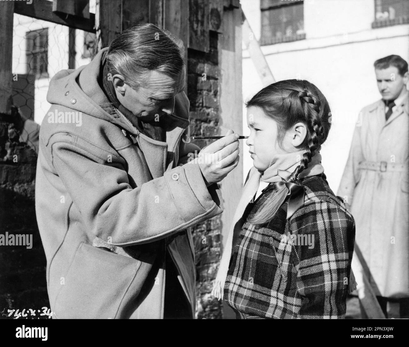 Make Up Artist (likely HARRY FRAMPTON)  touches up make-up on MANDY MILLER on set candid during filming of MANDY 1952 director ALEXANDER MACKENDRICK adapted from The Day is Ours by Hilda Lewis screenplay Nigel Balchin and Jack Whittingham costume design Anthony Mendleson music William Alwyn producers Michael Balcon and Leslie Norman Michael Balcon Productions / Ealing Studios / General Film Distributors (GFD) Stock Photo